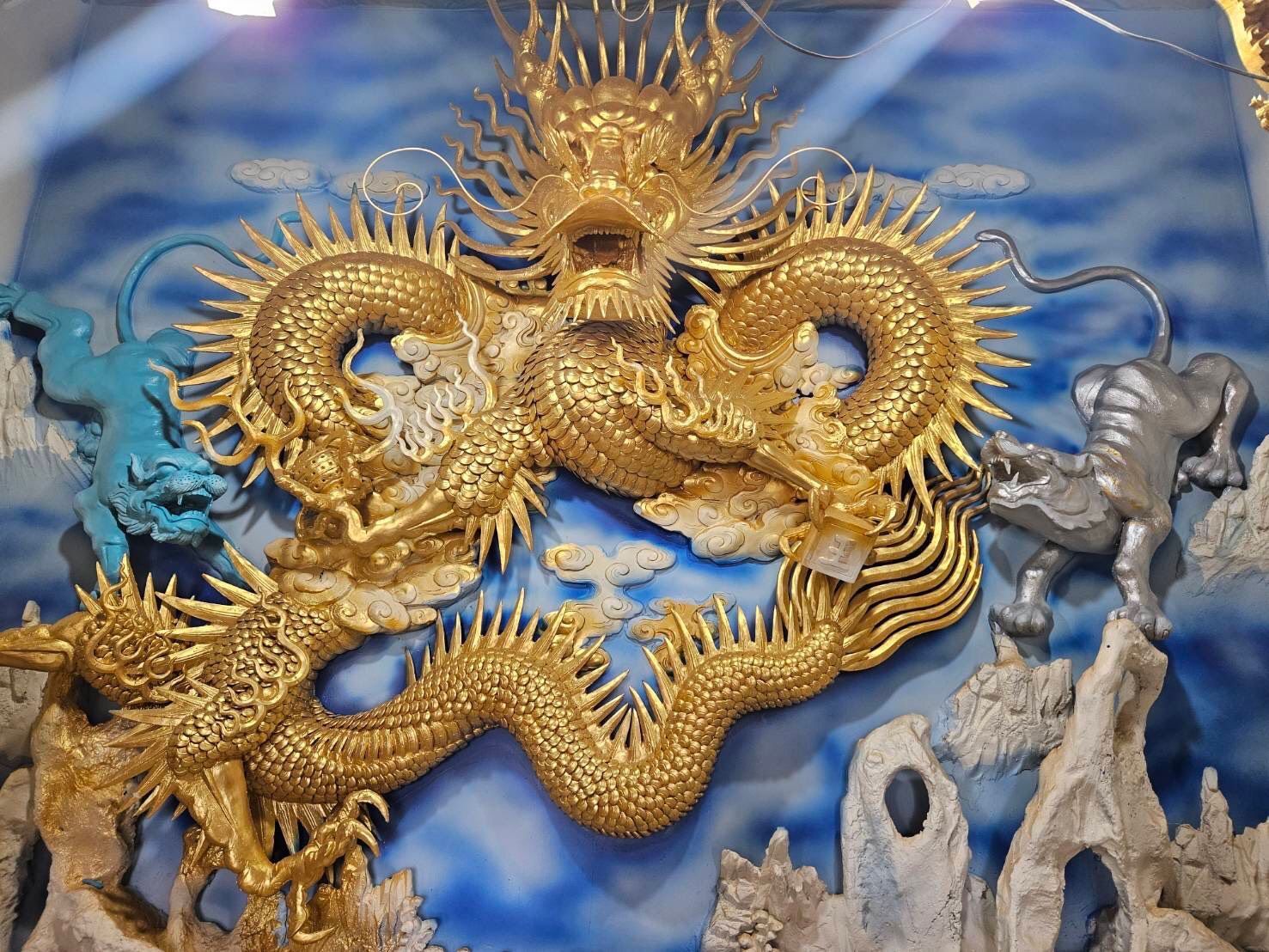 金色巨龍雕塑在藍灰色岩石背景上蜿蜒盤旋