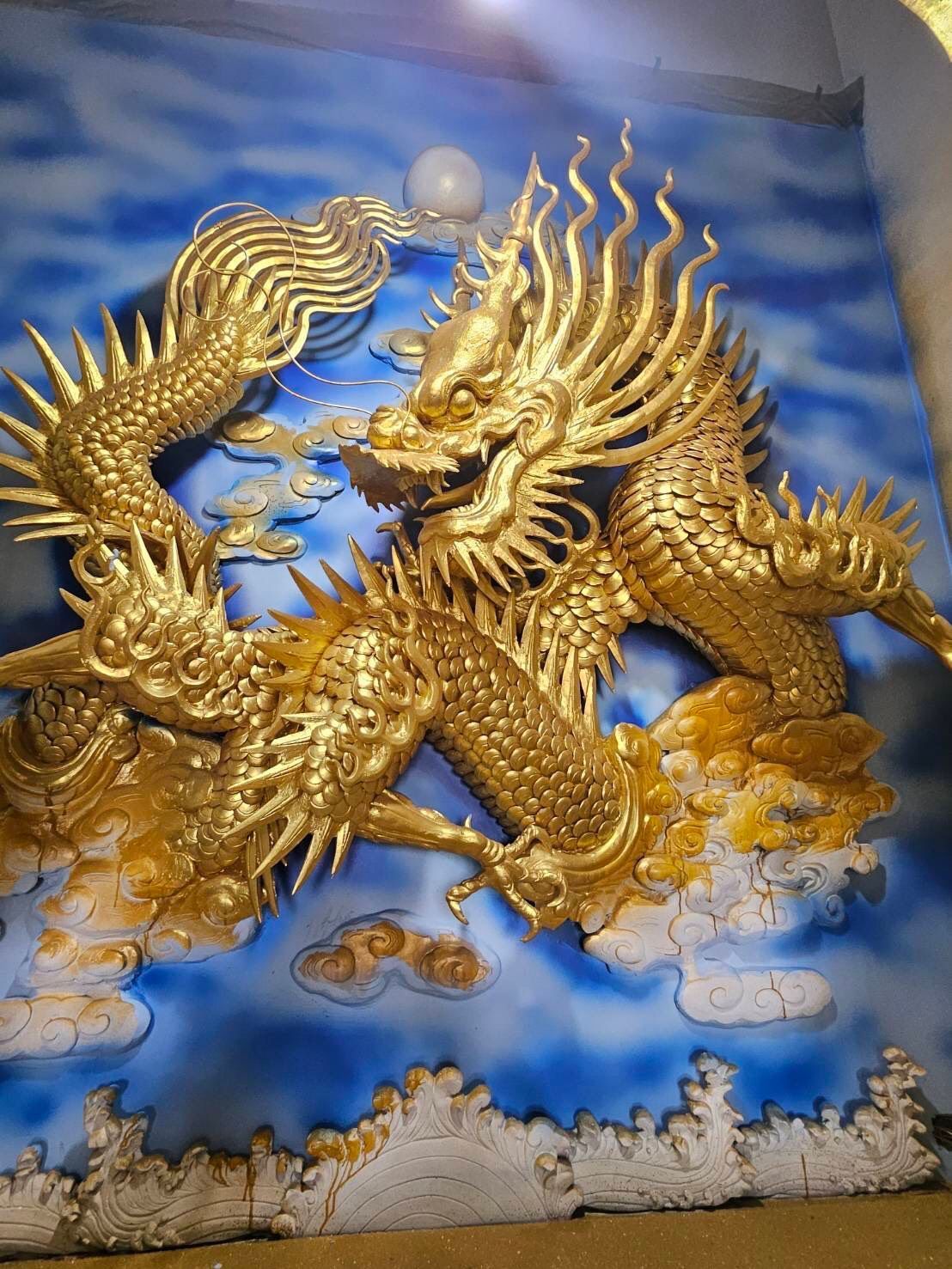 金色巨龍浮雕,背景是蔚藍多雲的天空