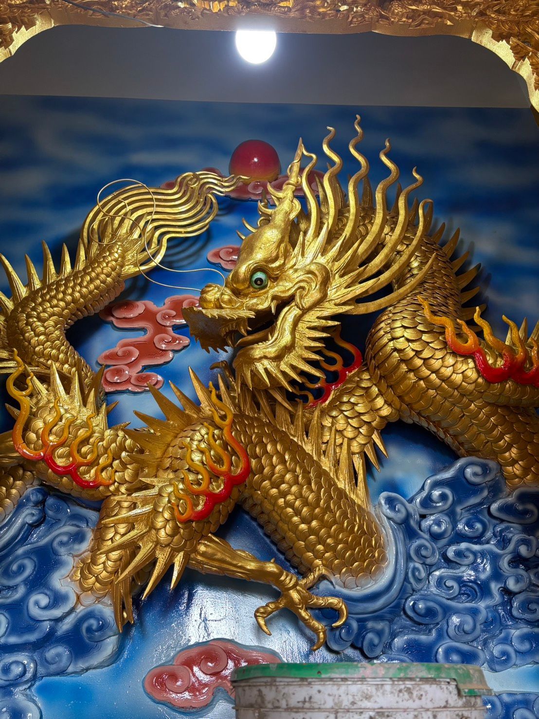 金色巨龍雕塑盤踞於碧水之上,纏繞著一顆紅珍珠,飾以華麗的紅金紋飾。