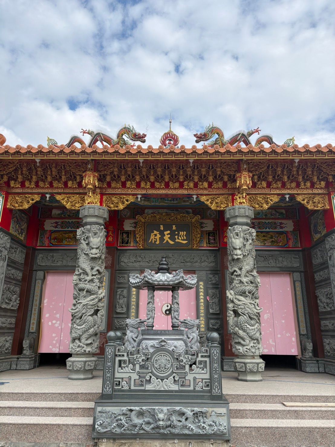 傳統中國寺廟入口,帶有精美的龍形屋頂、石柱和中央香爐。