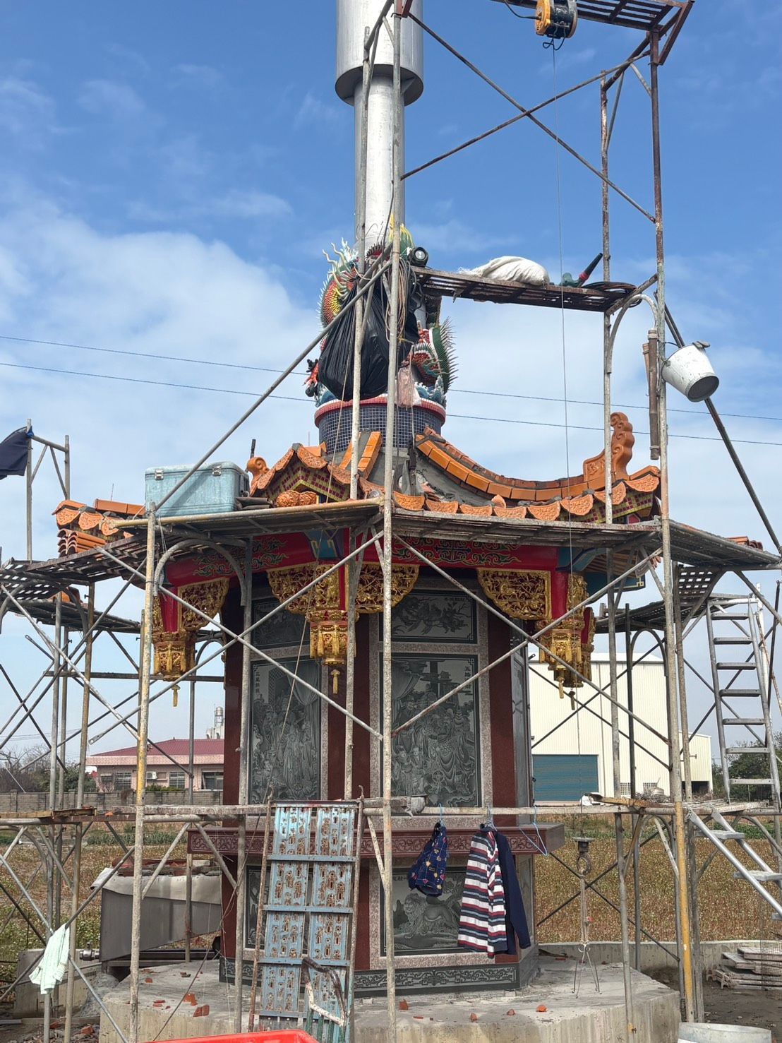 一座正在修繕的小廟屋頂周圍搭起了鷹架,工人們在上面作業,下面飄揚著一面美國國旗。