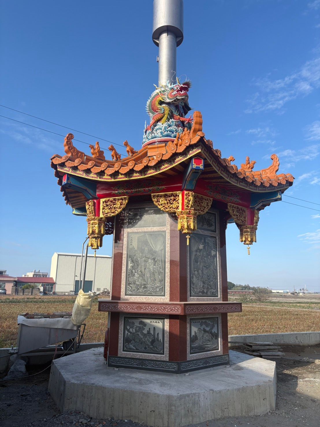 藍天下,一座華麗的中式神龕矗立在混凝土基座上,紅柱金頂,氣勢恢宏,掩映在一片藍天之下。