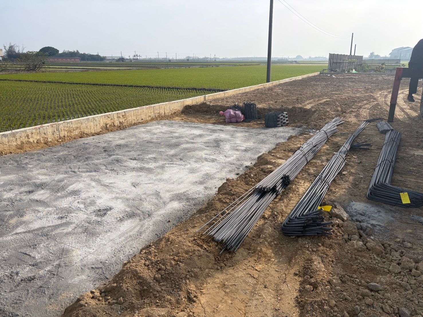 綠地旁是道路施工現場,正在進行礫石樁和混凝土基礎施工。