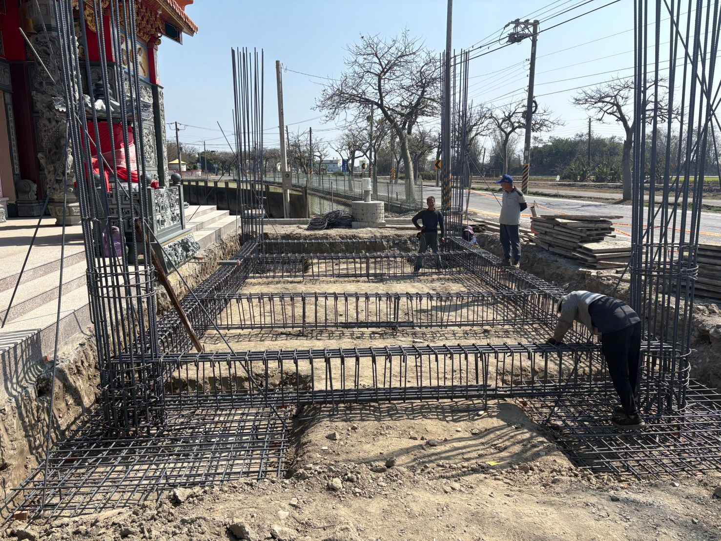 晴空萬裡下,建築工地上鋼筋混凝土基礎溝槽和工人正在施工。