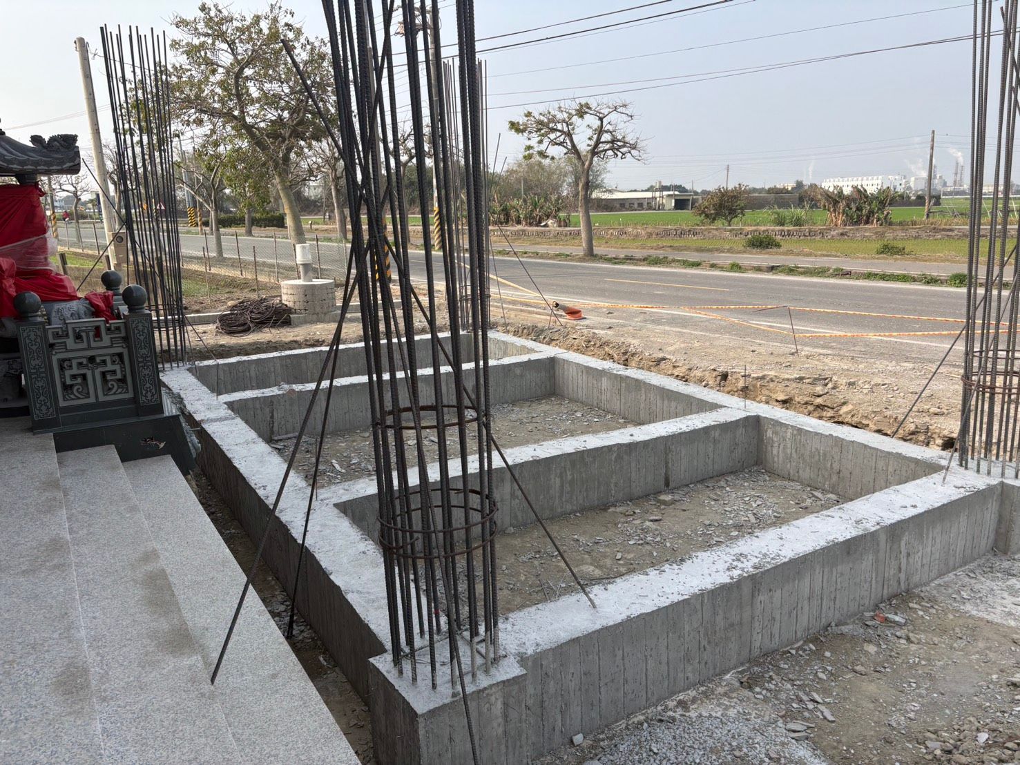 路邊建築工地旁,鋼筋混凝土基礎和低矮的磚牆。