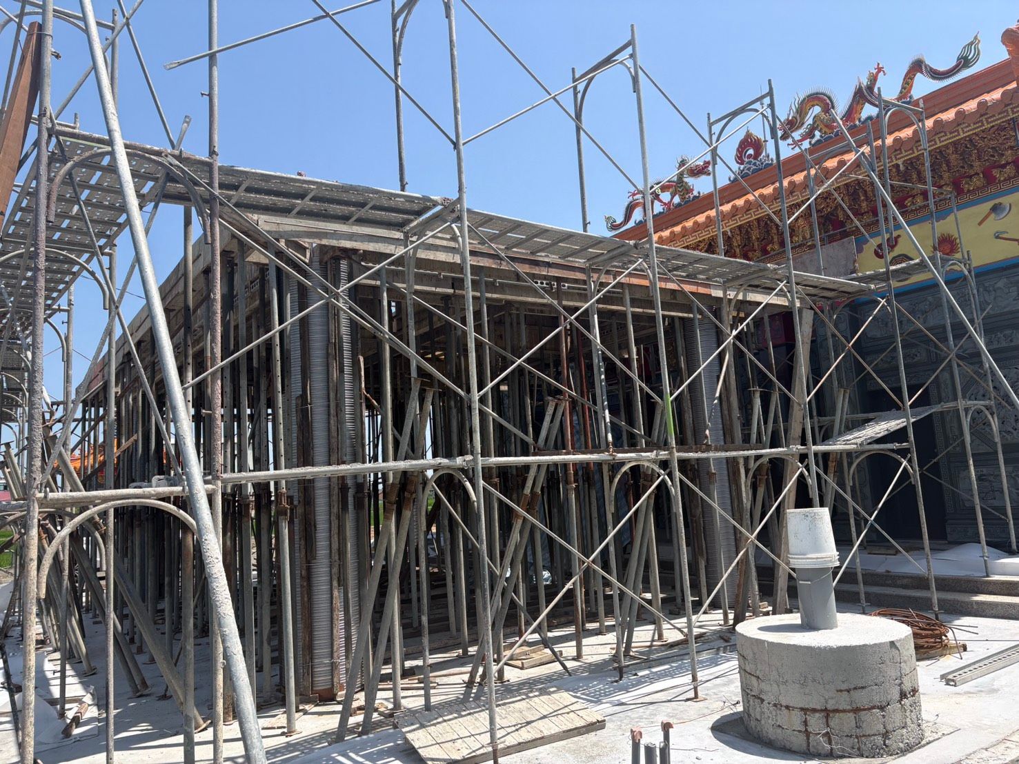 藍天下,建築工地上搭著小型鷹架,豎立著金屬桿。