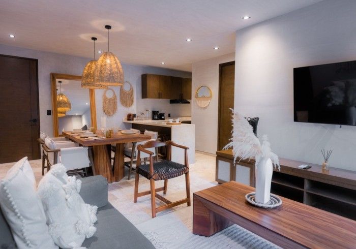 Una sala de estar con sofá, mesa, sillas y televisor de pantalla plana. Hotel Bakal Tulum