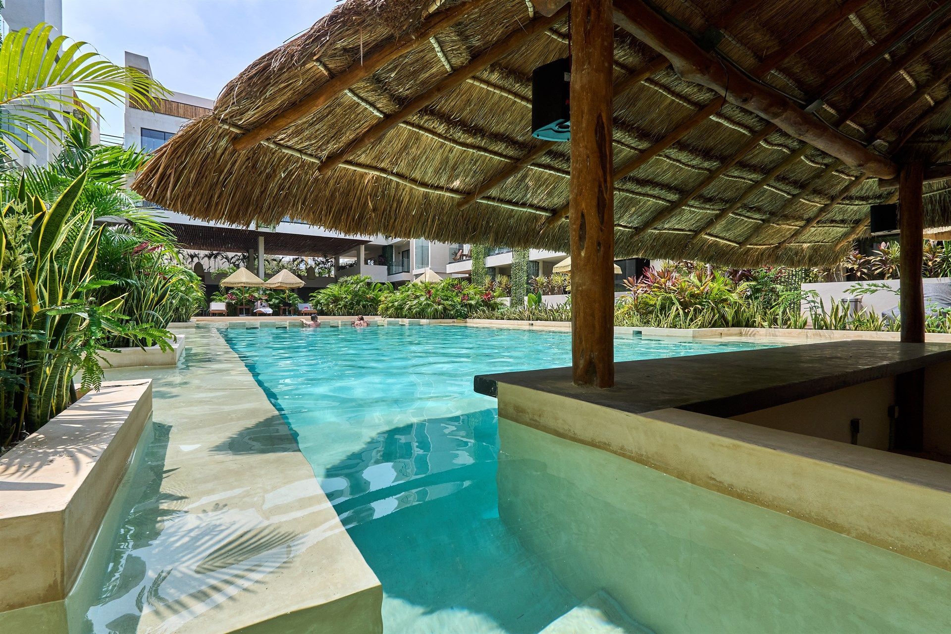 Una piscina con techo de paja y un bar. Hotel Bakal Tulum