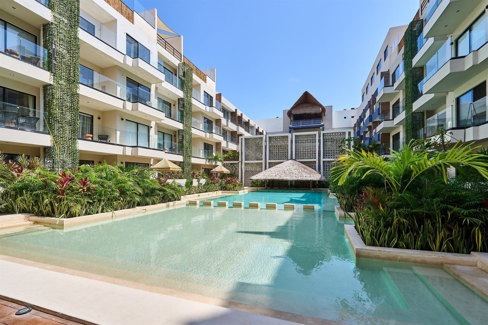 Hay una gran piscina en el medio de un edificio. Hotel Bakal Tulum