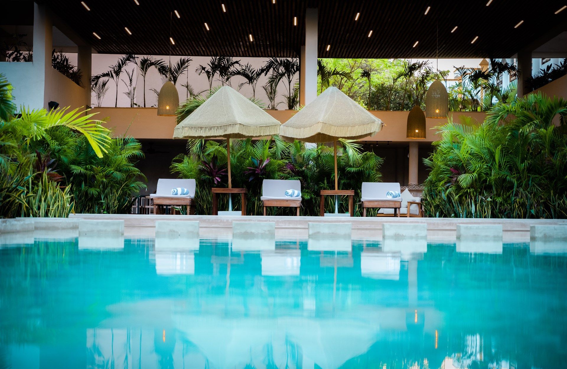 Una gran piscina rodeada de sillas y sombrillas en un hotel. Hotel Bakal Tulum