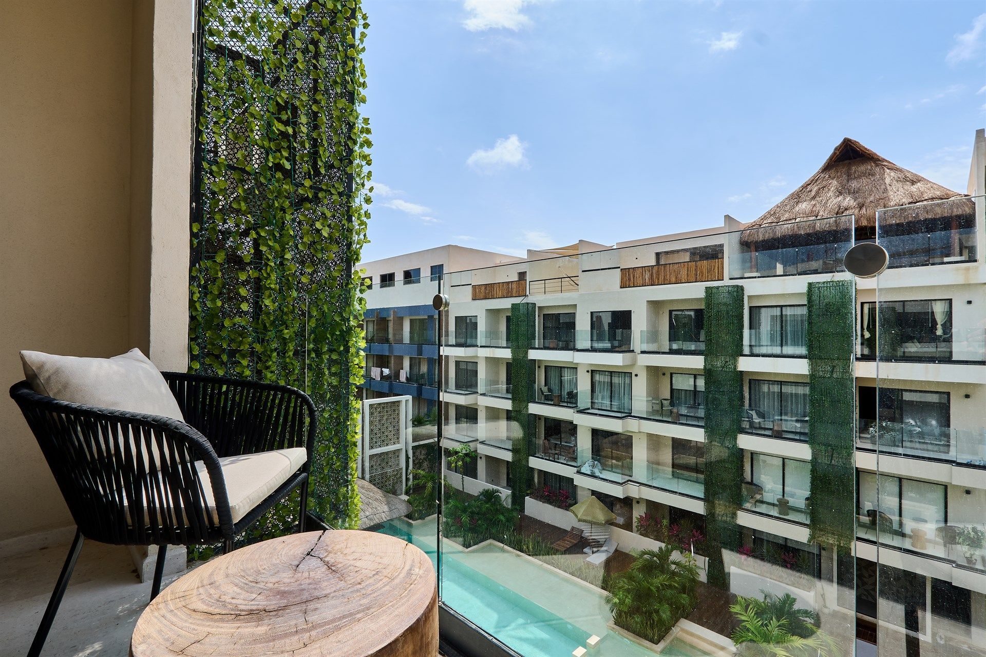Un balcón con una silla y una mesa con vista a una piscina. Hotel Bakal Tulum