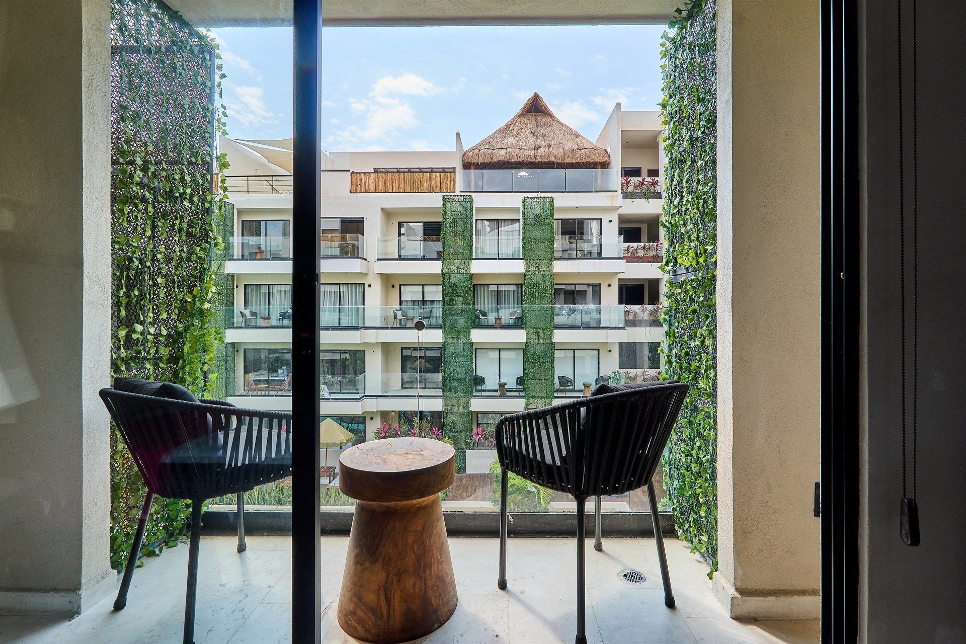 Un balcón con dos sillas y una mesa con vista a un edificio. Hotel Bakal Tulum