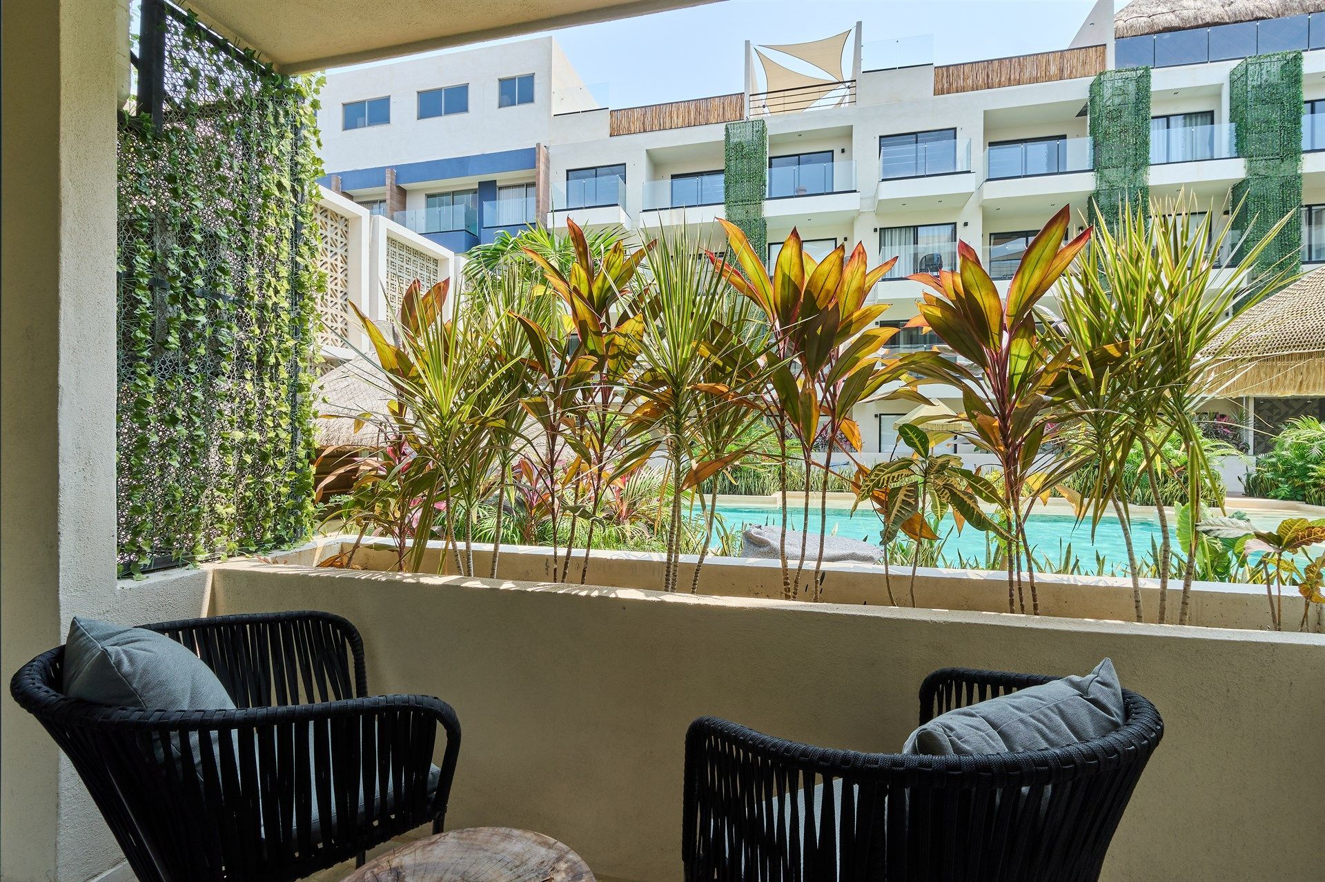 Dos sillas están sentadas en un balcón con vista a una piscina. Hotel Bakal Tulum