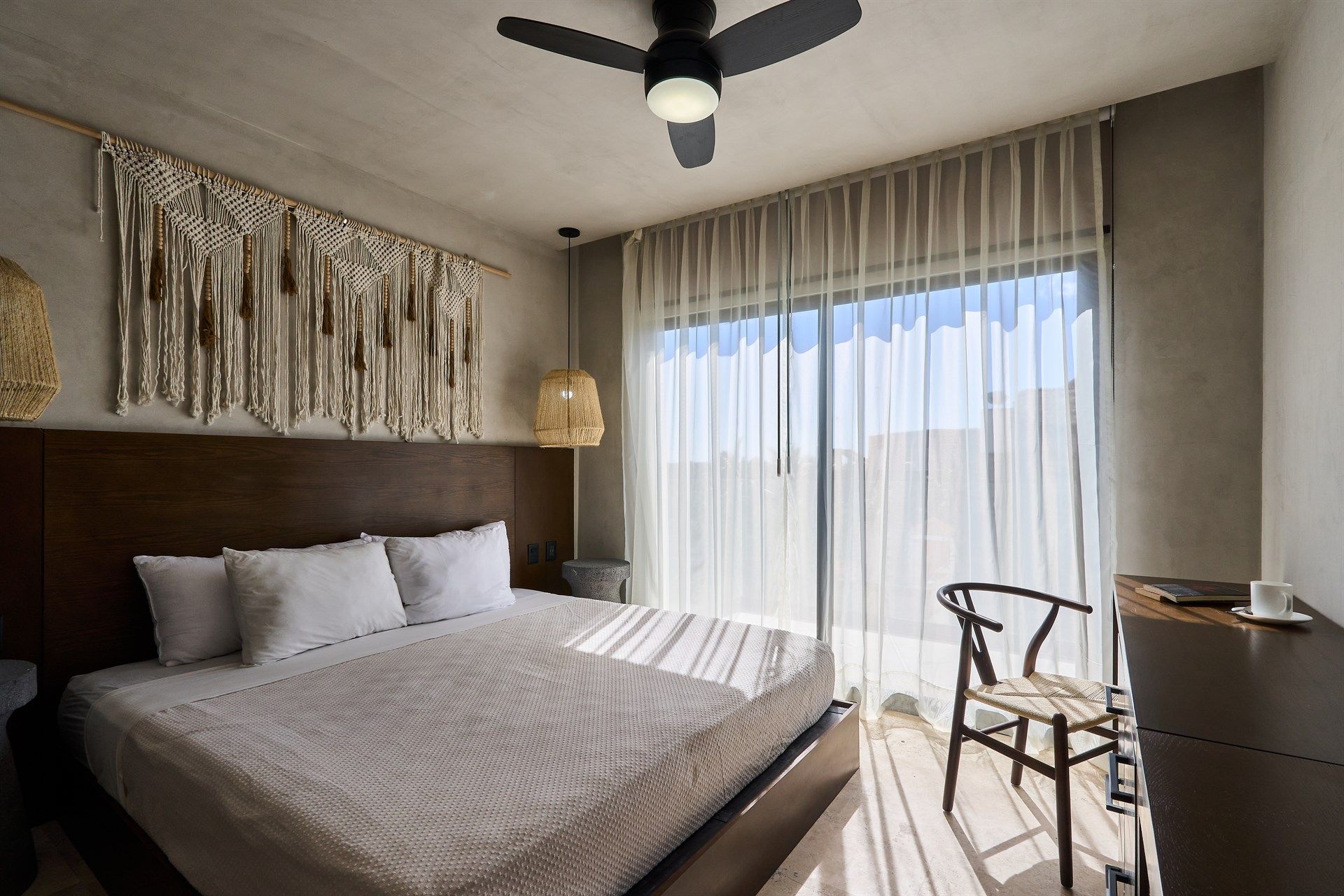 Un dormitorio con una cama grande, silla, escritorio y ventilador de techo. Hotel Bakal Tulum