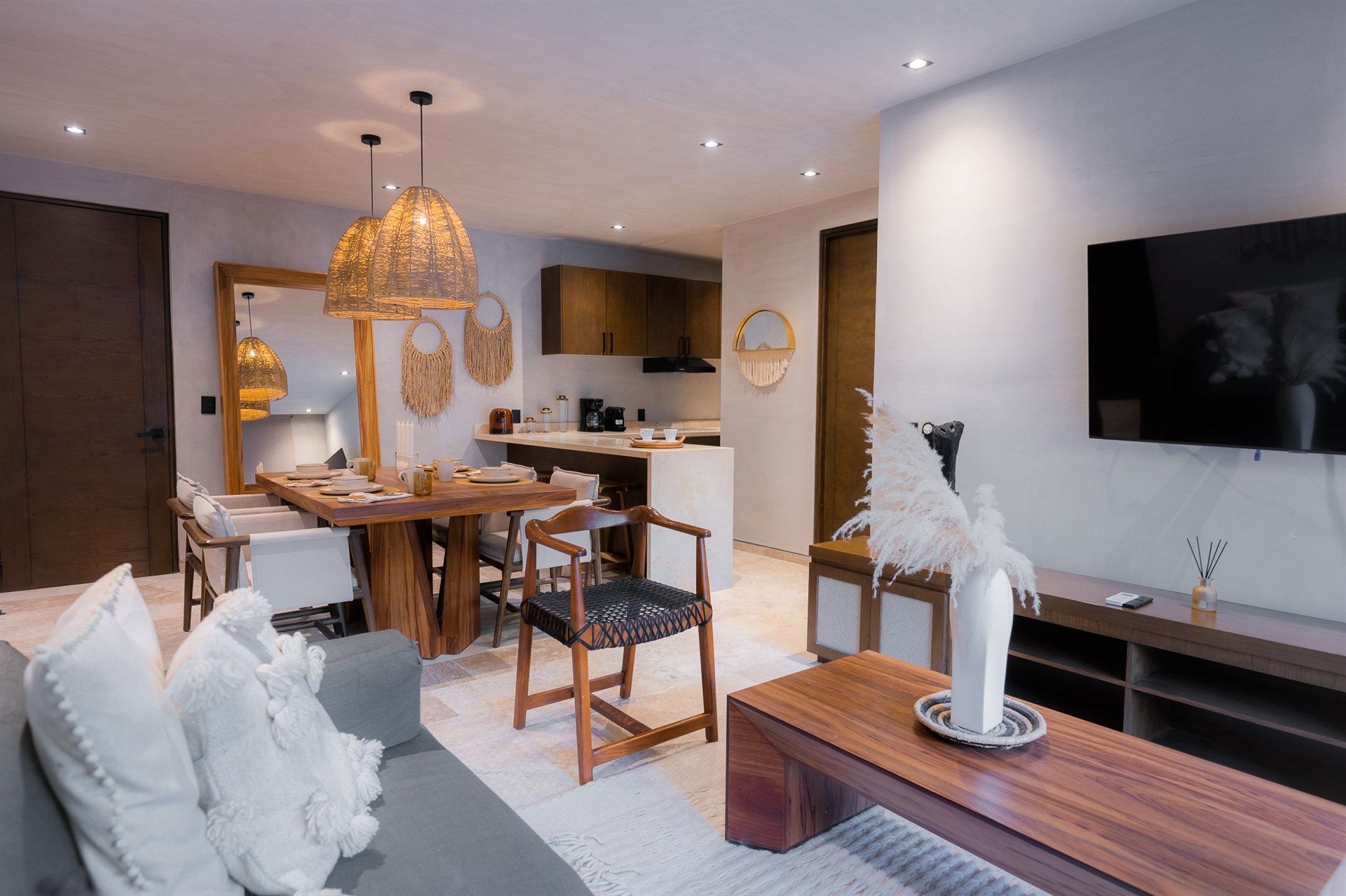 Una sala de estar con sofá, mesa, sillas y televisor de pantalla plana.