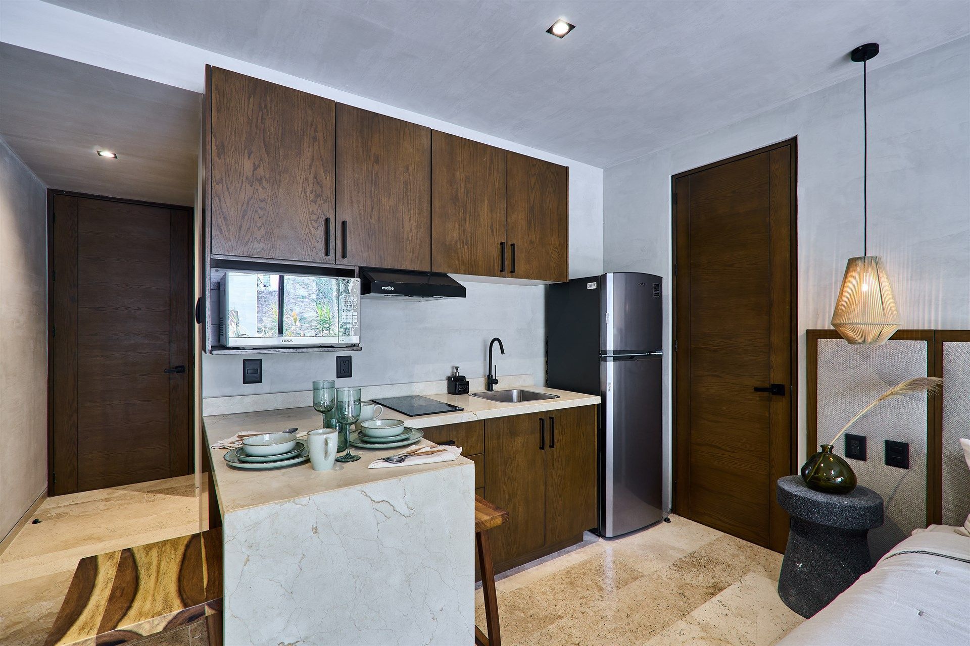 Una cocina con electrodomésticos de acero inoxidable y gabinetes de madera. Hotel Bakal Tulum