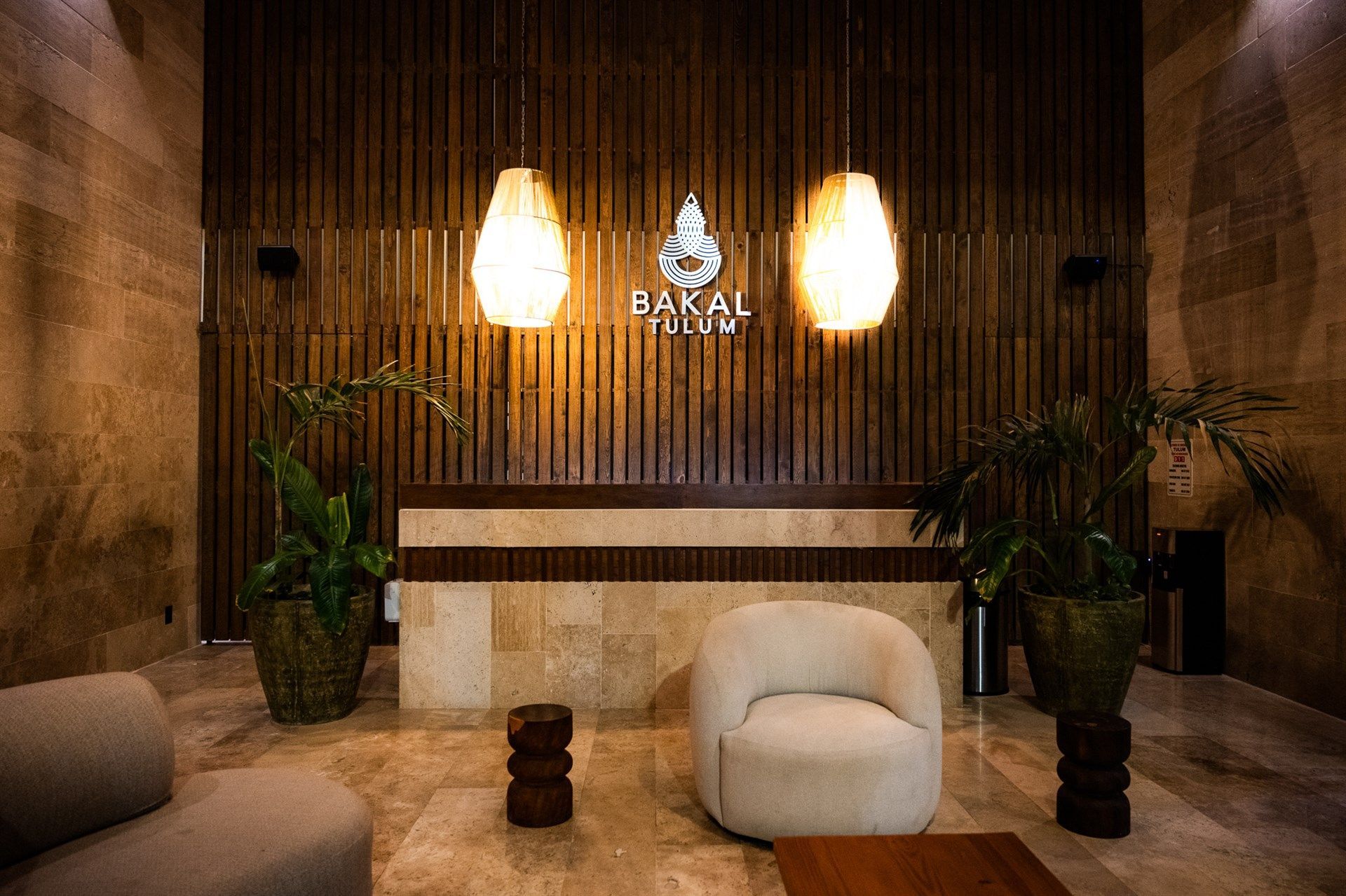 Una sala de estar con sofá, silla, mesa y plantas. Hotel Bakal Tulum