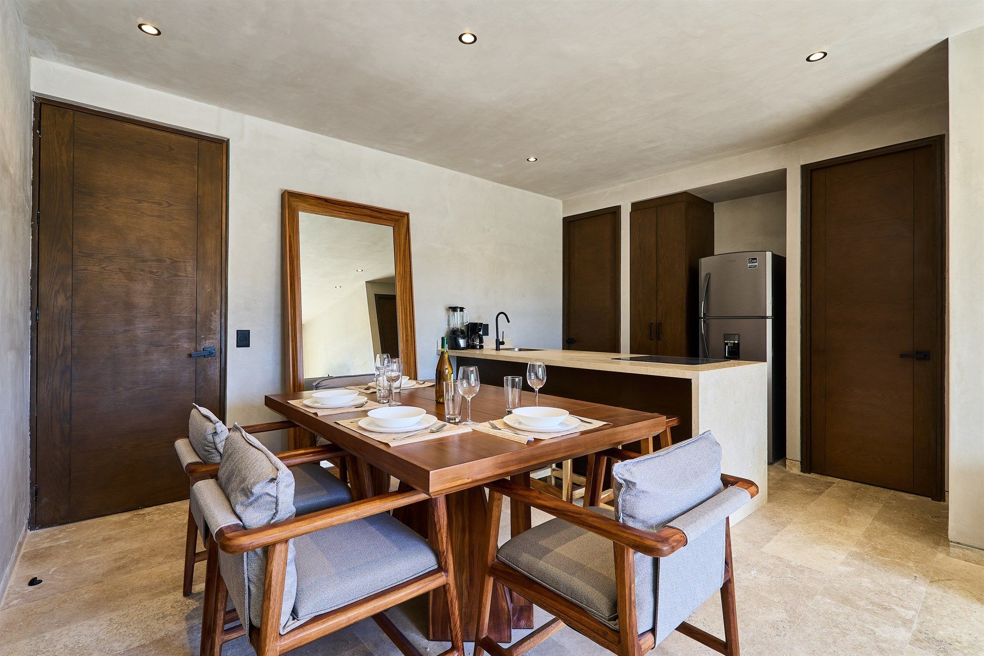 Un comedor con mesa y sillas de madera y un gran espejo. Hotel Bakal Tulum