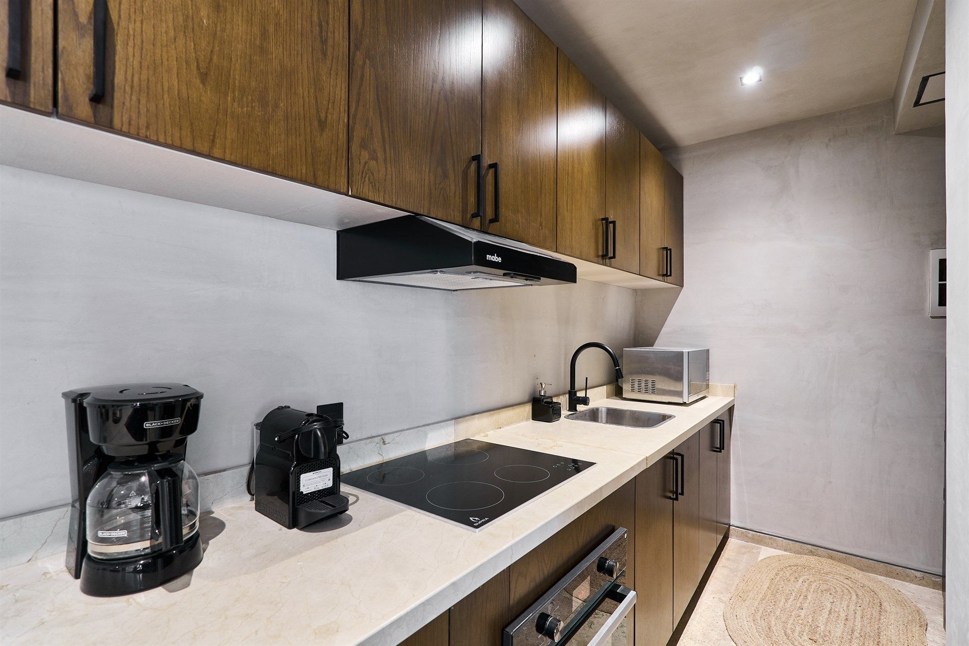 Una cocina con gabinetes de madera y una cafetera en el mostrador. Hotel Bakal Tulum