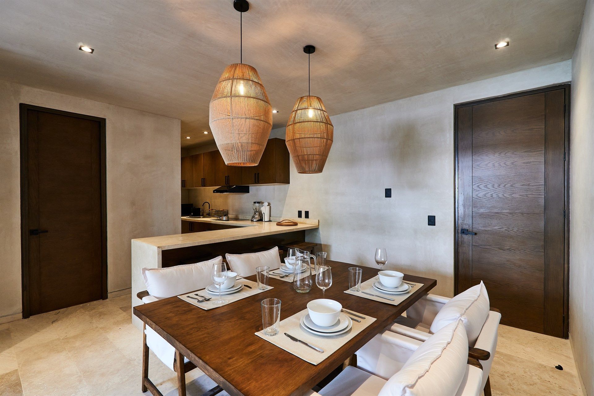 Un comedor con mesa y sillas de madera y una cocina al fondo. Hotel Bakal Tulum