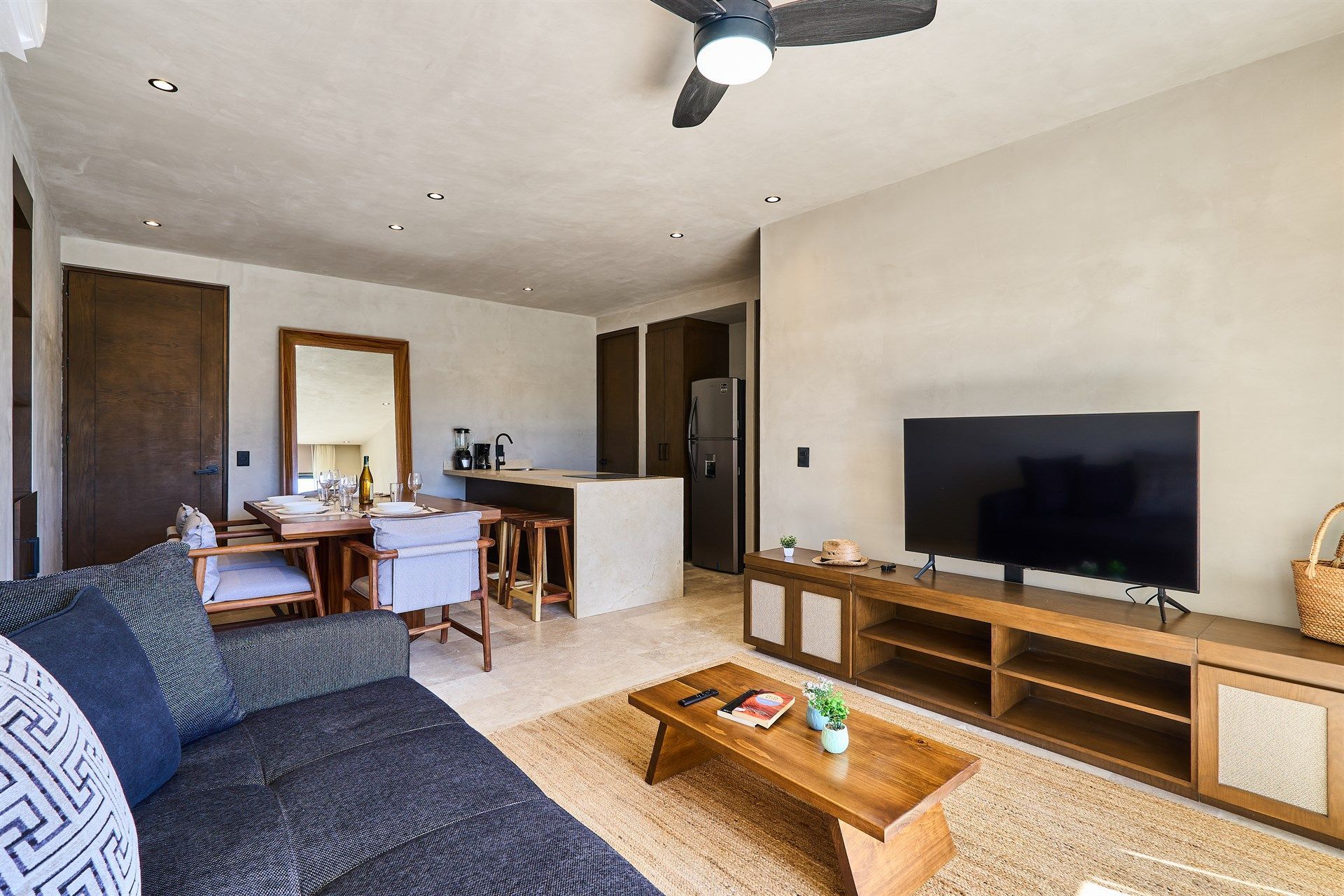Una sala de estar con sofá, televisión, mesa de café y ventilador de techo. Hotel Bakal Tulum