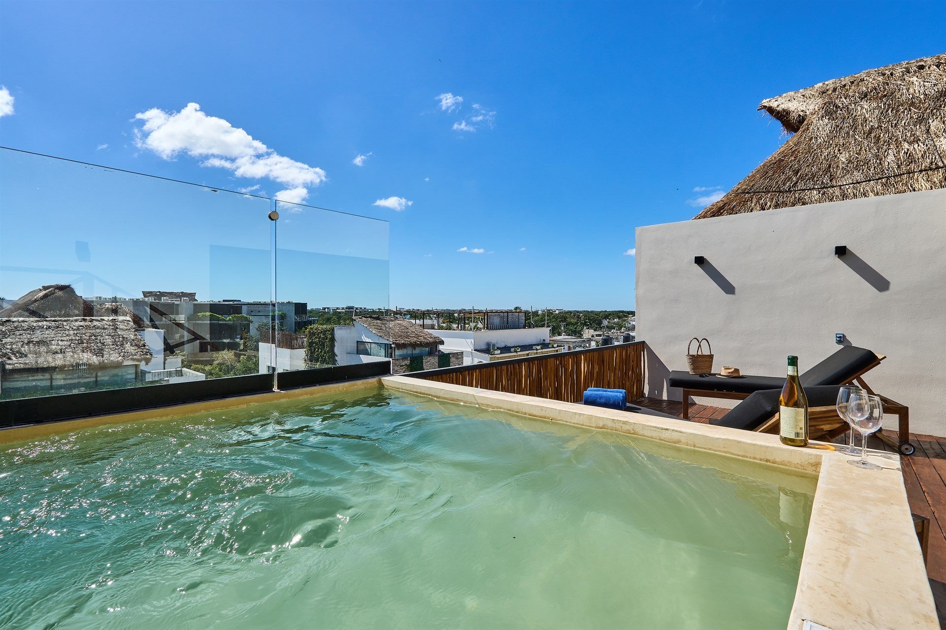 Una piscina con vista a la ciudad y techo de paja. Hotel Bakal Tulum