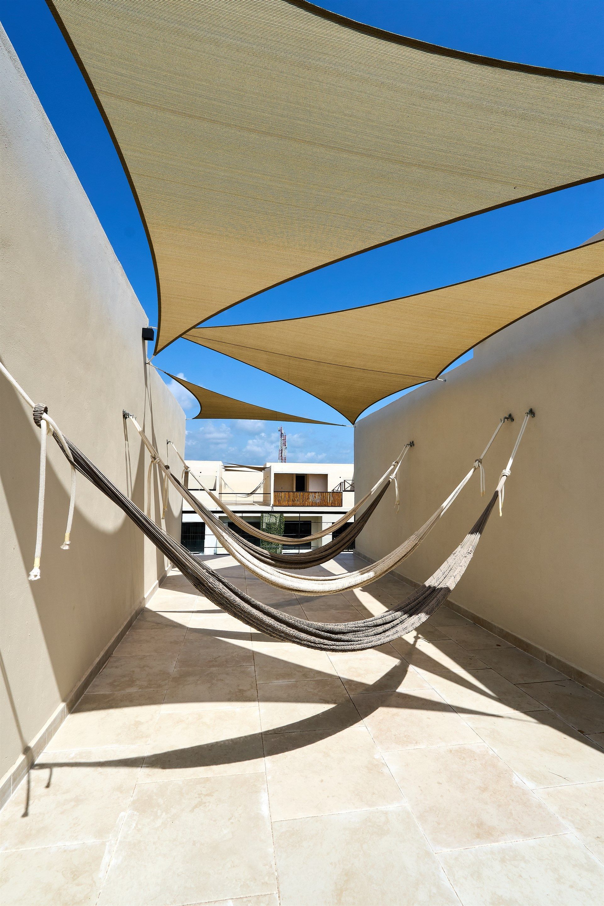 Una hamaca está colgada de una pared debajo de una sombrilla. Hotel Bakal Tulum