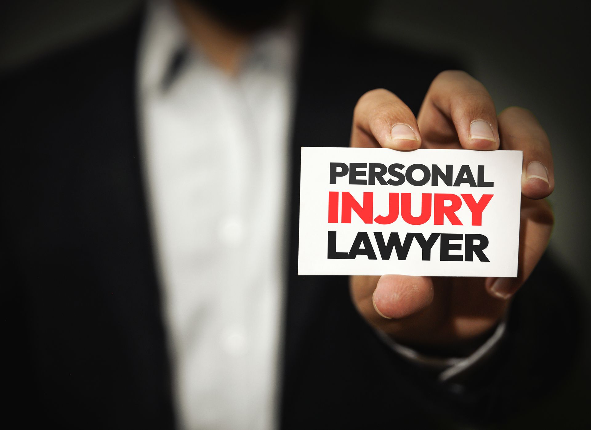 Personal injury lawyer holding a card with text, offering legal help for injury cases.