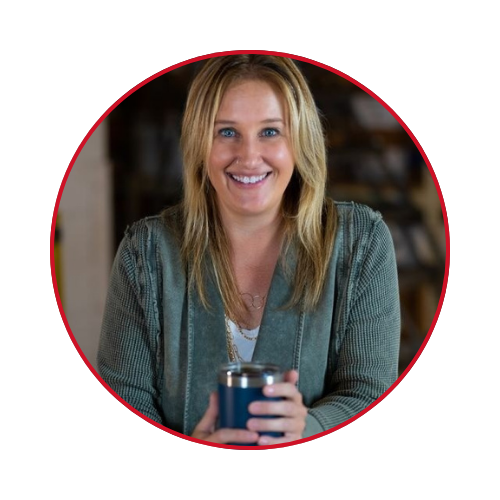 A woman in a green sweater is holding a blue cup and smiling.