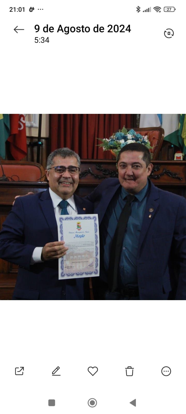 Dois homens de terno e gravata estão de pé, um ao lado do outro, segurando um certificado.