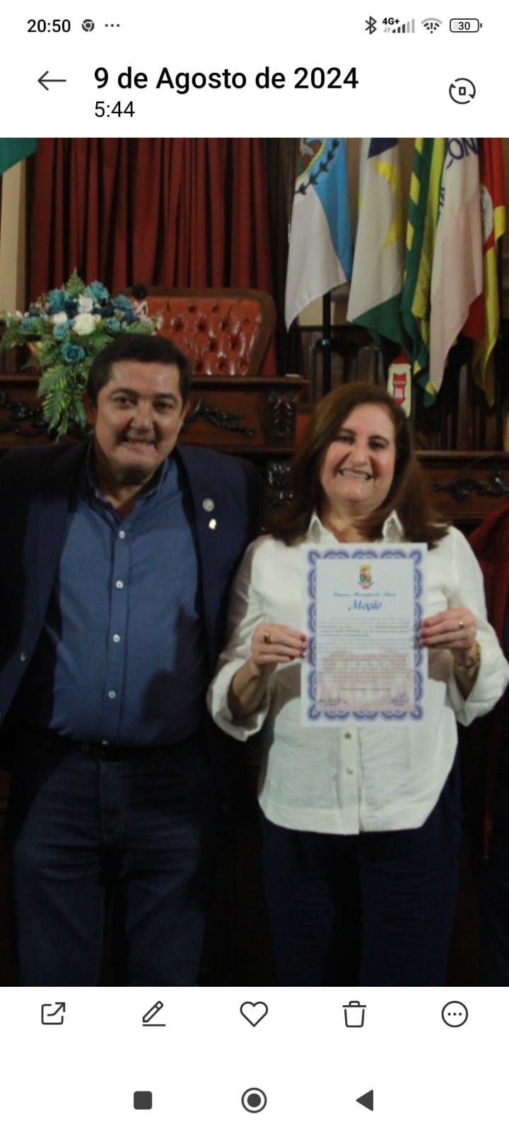 Um homem e uma mulher estão de pé, um ao lado do outro, segurando um certificado.