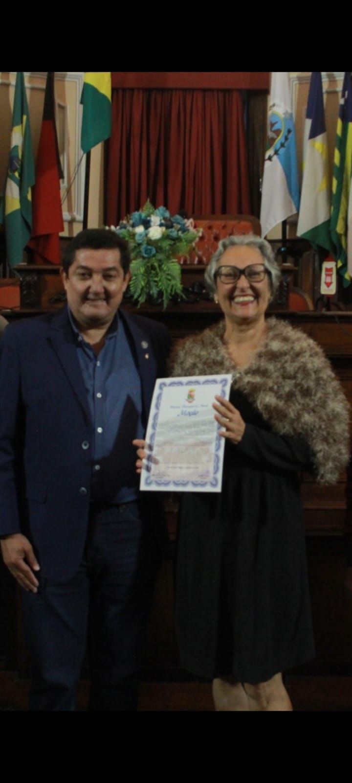 Um homem e uma mulher estão de pé, um ao lado do outro, segurando um certificado.