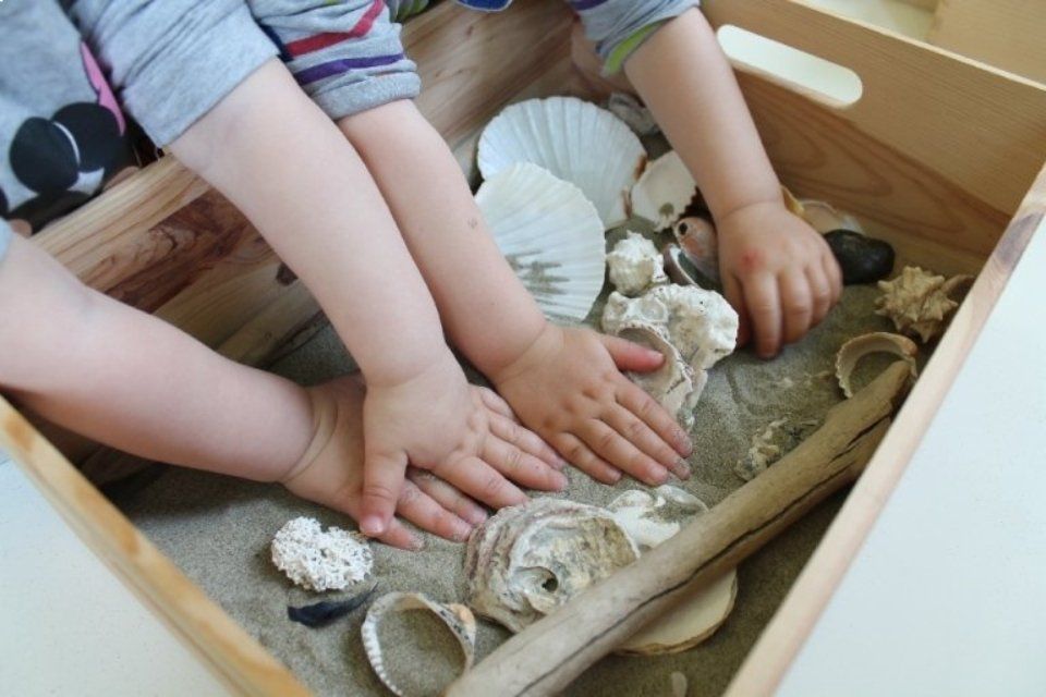 Bambini che giocano con sabbia e conchiglie