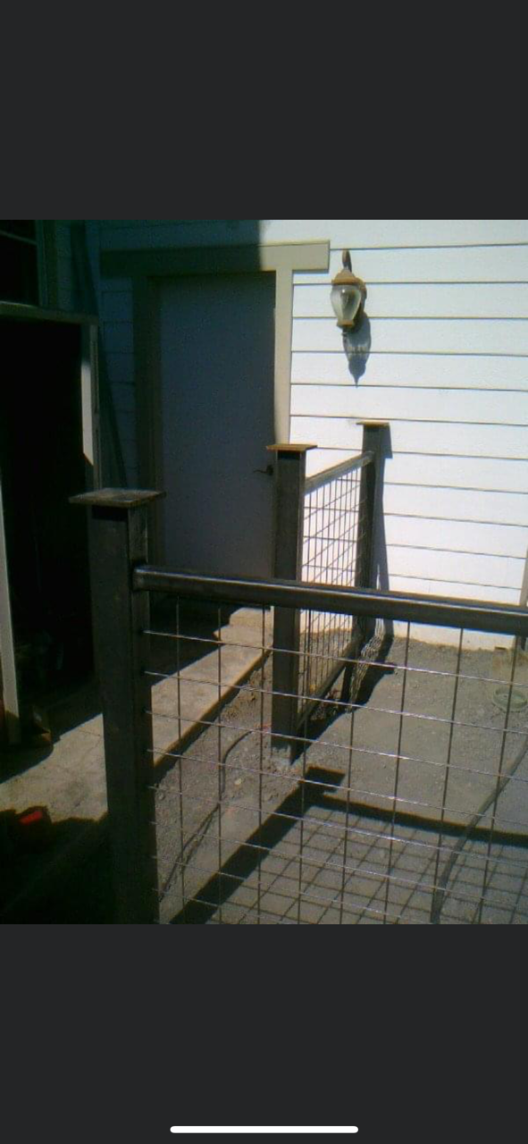 Fence with wire mesh railing in front of a white house with a hanging light.