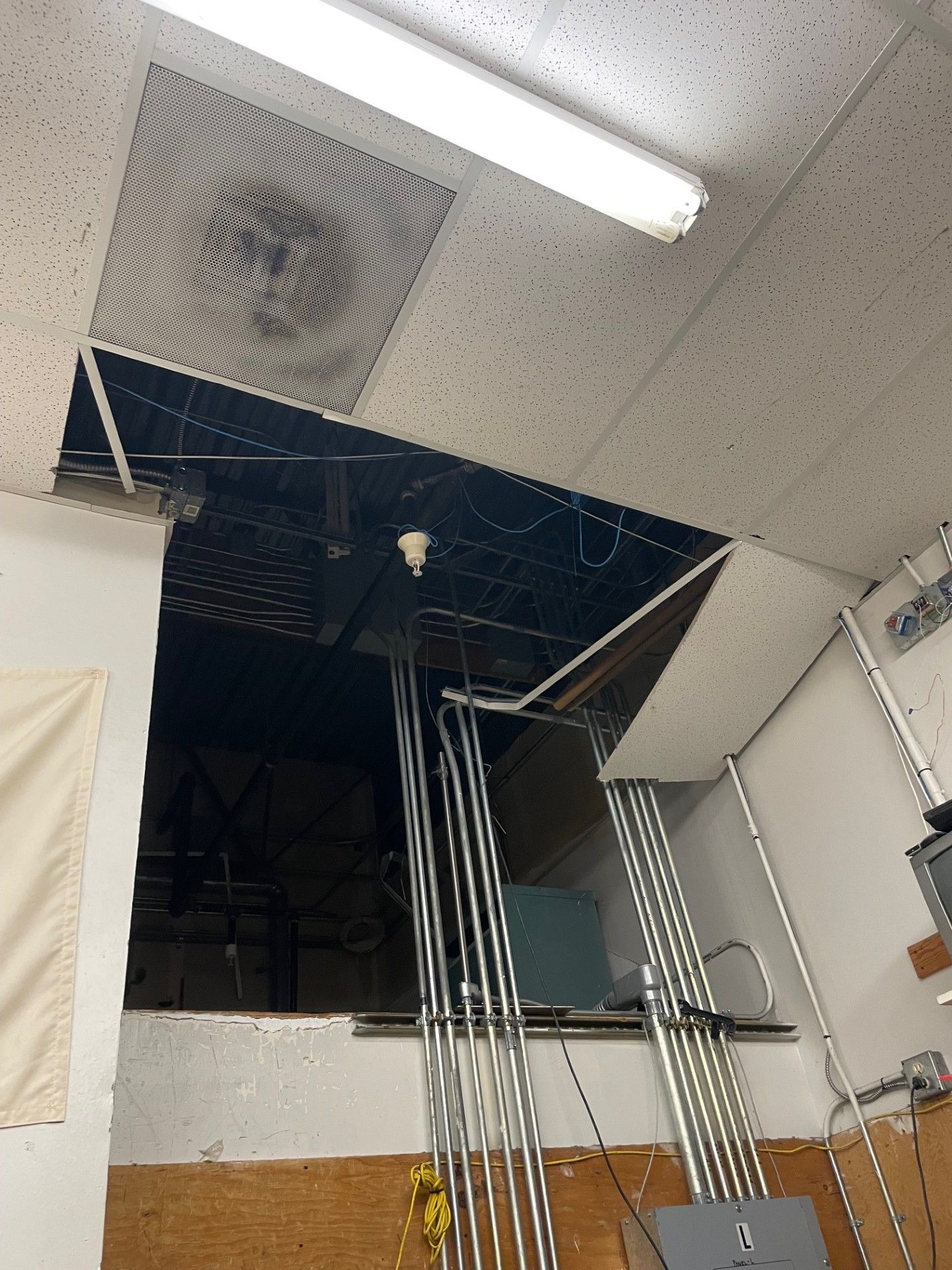 Damaged ceiling with a large hole revealing electrical wiring and a light fixture.