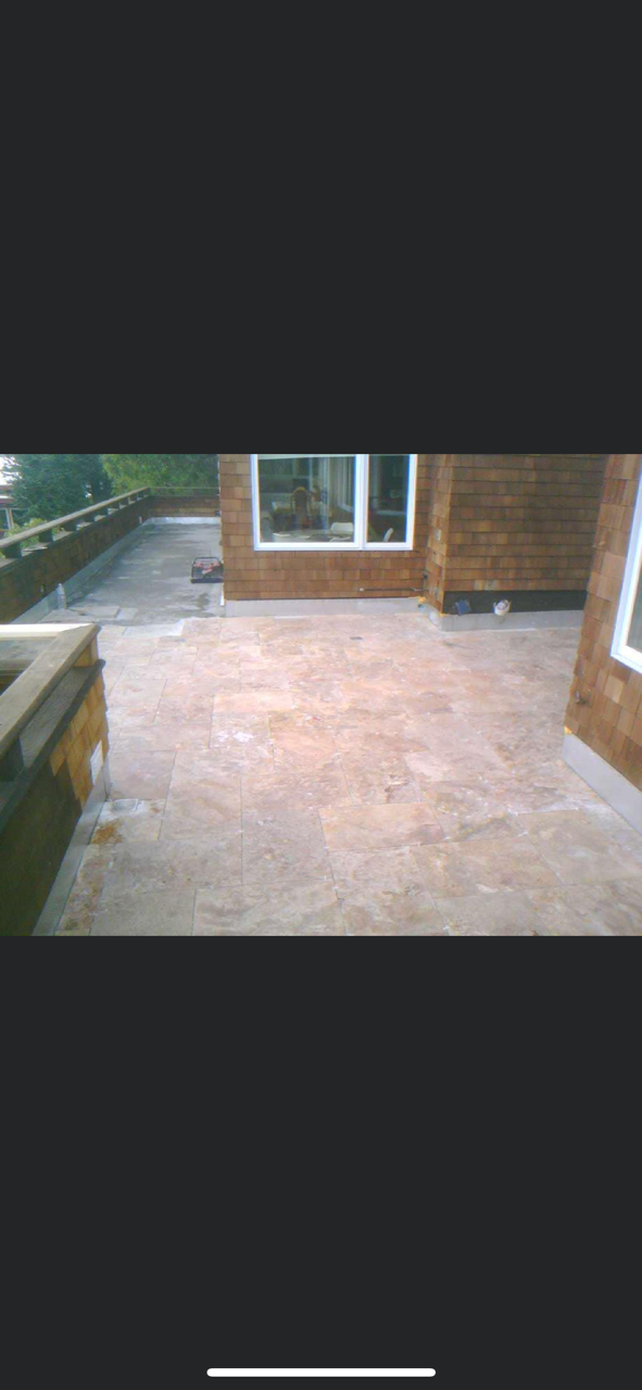 A brick building with a concrete patio. A window is visible on the building.