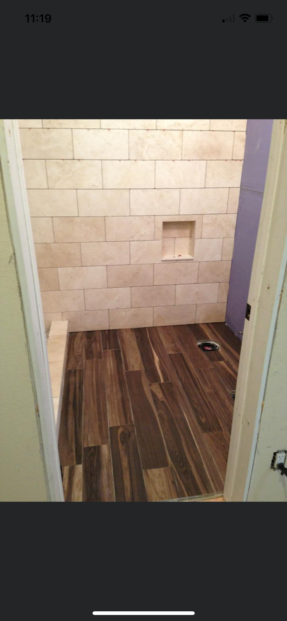 Bathroom with tile walls, wood-look floor, and built-in shelf.