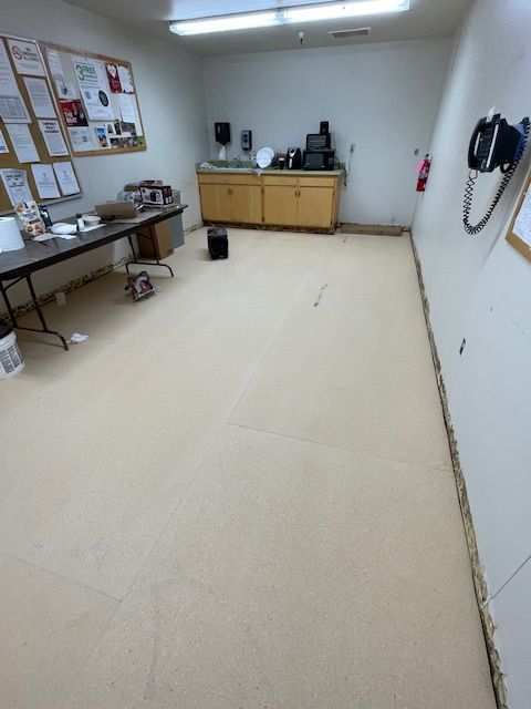 An empty room with beige flooring, cabinets, and a bulletin board on the wall.