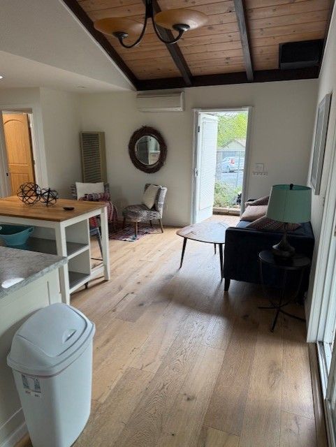 Living room with wood floor, white walls, and a wood ceiling.