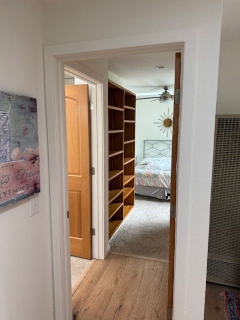 Hallway leading to a bedroom with bookshelves on one side and a closed door on the other.