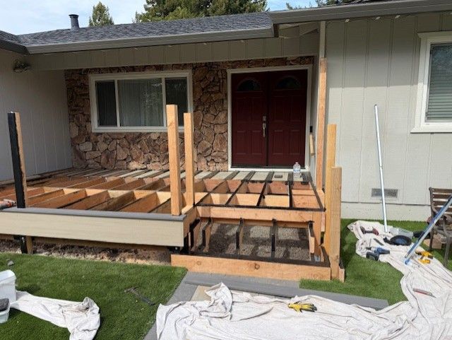 Front porch under construction; wooden frame and steps; door visible; tools on ground.