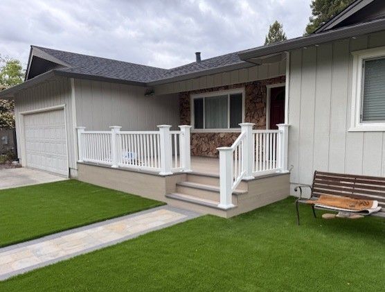 House exterior with a white railing porch, steps, and green lawn.