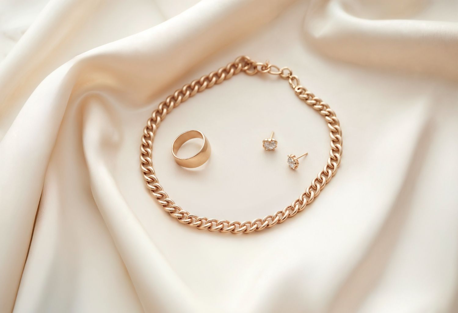 Conjunto de joyas en tono dorado, que incluye un collar de cadena, un anillo y dos pendientes de botón