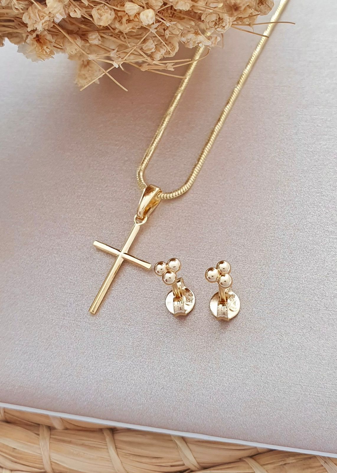 Un collar de oro con un colgante en forma de cruz y un par de pendientes pequeños