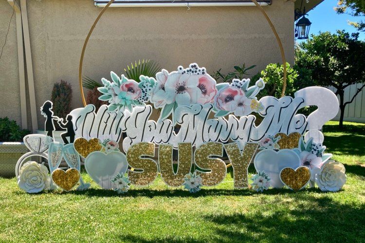 Proposal yard card. Will you marry me with rings, champagne, hearts, and flowers. 