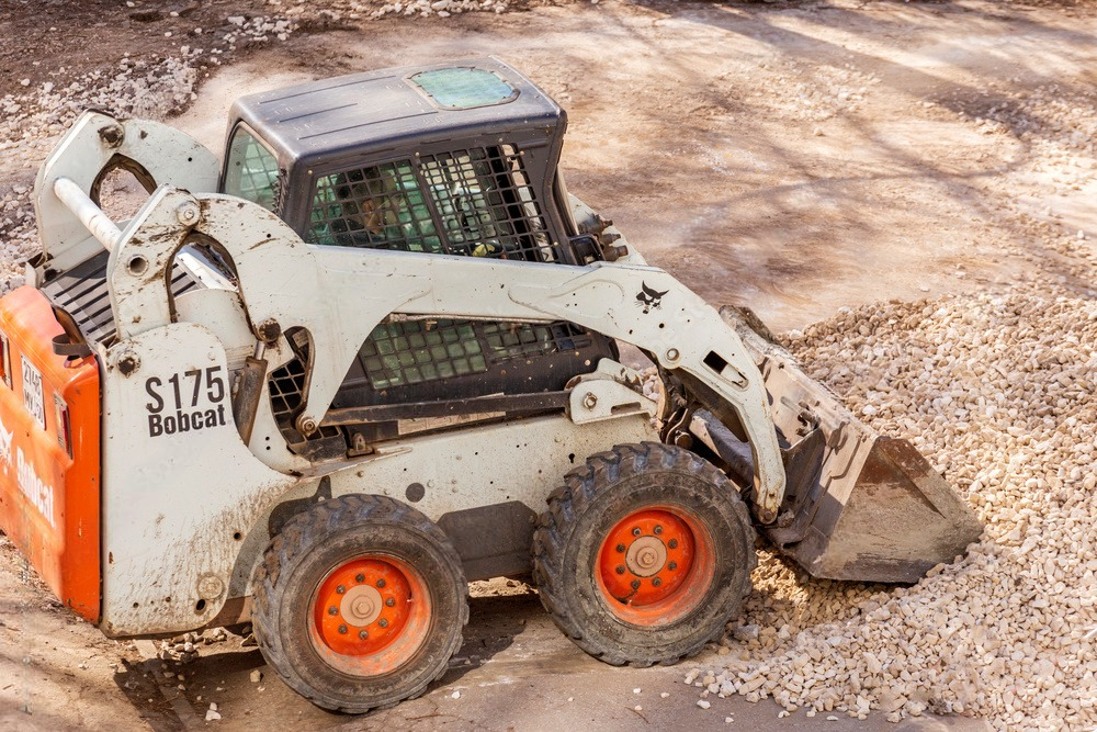 A bobcat skid steer is sitting on top of a dirt road.