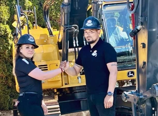 A yellow excavator is sitting on top of a pile of gravel.