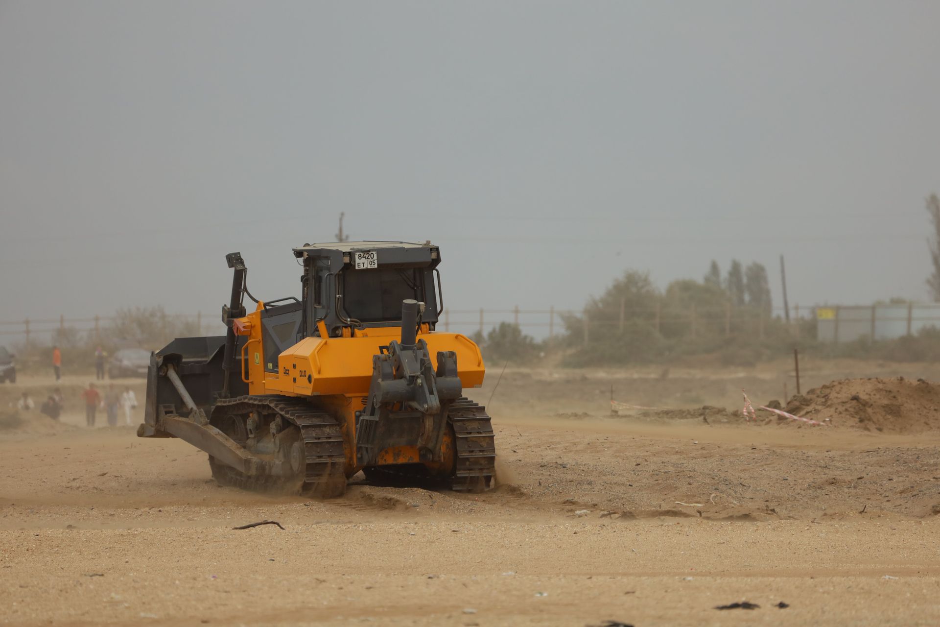 A bulldozer is driving through a dirt field.