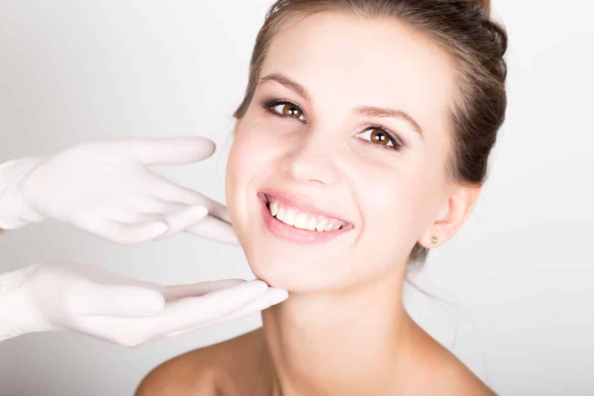 A woman is smiling while getting a botox injection in her face.