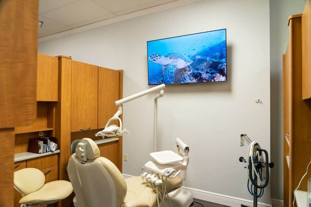 A dental office with a dental chair and a television on the wall.